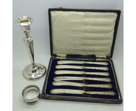 A silver candlestick, a silver napkin ring and knives with silver covered handles