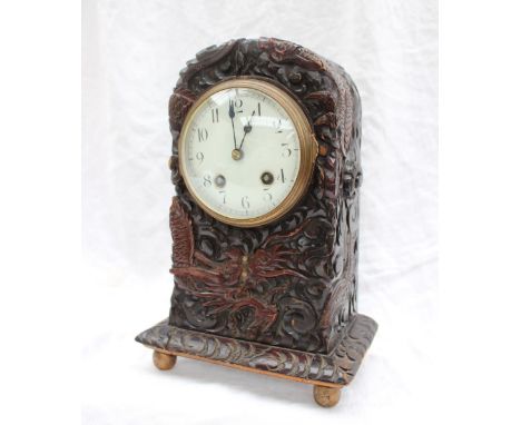 A Chinese inspired mantle clock, carved with a dragon amongst clouds, on ball feet, the circular dial with Roman numerals, st