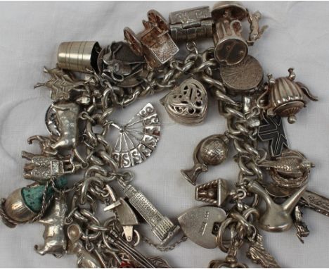 A silver charm bracelet, set with numerous charms including a crown, empire state building, lantern, gondola, globe, pig, tea