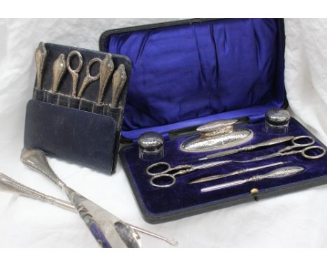 An Edward VII silver nail kit, with hammered decoration, including a nail buffer, two glass dressing table pot, scissors, nai