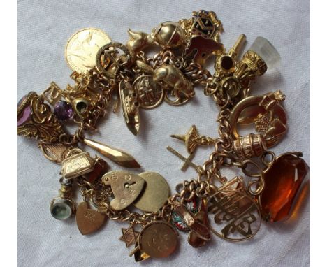 A 9ct yellow gold charm bracelet set with numerous charms including a canoe, tankard, key, elephant, half sovereign, cruise l