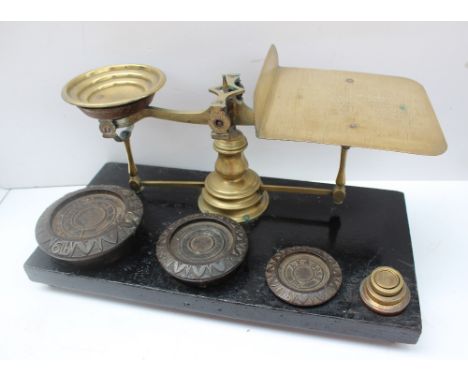 A pair of postal scales and weights, with a wooden base, brass pan and scales, with cast iron and brass weights 45cm wide x 2