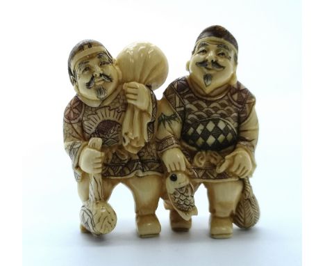 A signed carved ivory Japanese netsuke of two men one with a fish one with a mallet and a sack