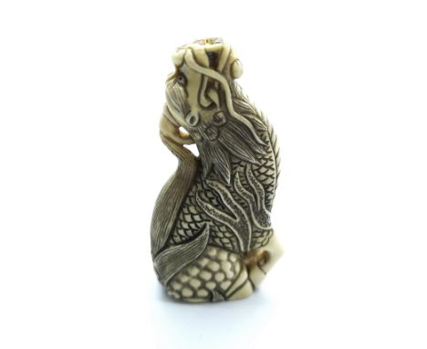 A signed carved ivory Japanese netsuke of a sitting dragon
