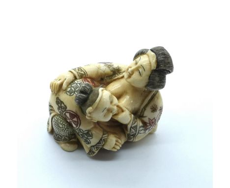 A signed carved ivory Japanese netsuke of a woman breast feeding
