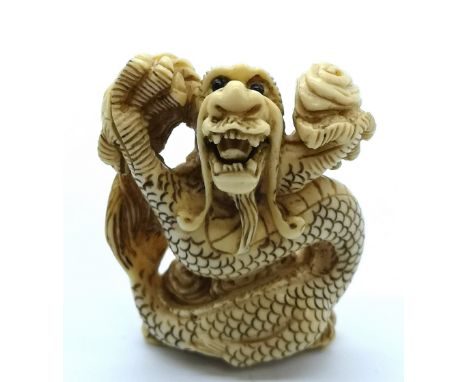 A signed carved ivory Japanese netsuke depicting a coiled dragon in flames