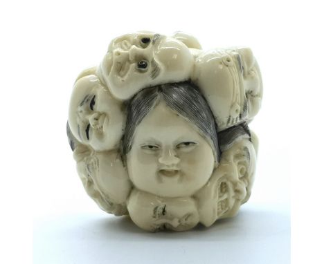 A signed carved ivory Japanese netsuke of twelve masks