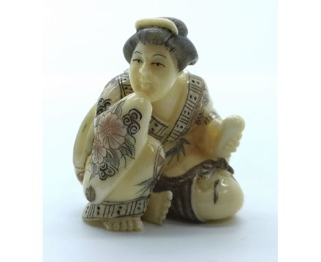 A signed carved ivory Japanese netsuke of a seated Geisha