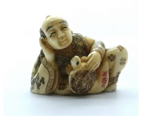 A signed carved ivory Japanese netsuke of a man with a turtle