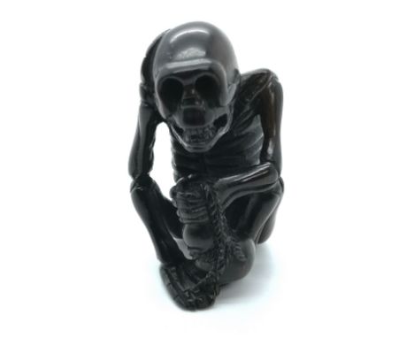 A fruitwood carved and signed Japanese netsuke of a seated skeleton
