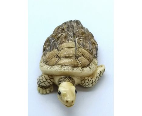 A carved and signed ivory Japanese netsuke of a sacred turtle with half shell half hair