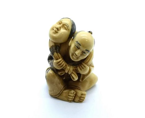 A signed carved ivory Japanese netsuke of a man carrying a child in a shawl on his shoulders