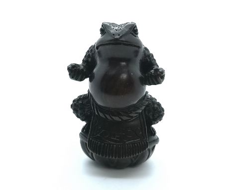 A carved and signed fruitwood Japanese netsuke of a Sumo wrestler toad challenging all comers