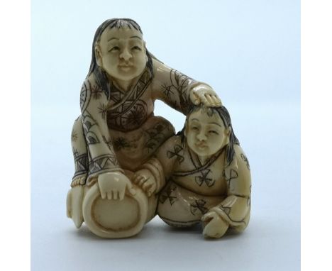 A signed carved ivory Japanese netsuke of a seated and a kneeling man