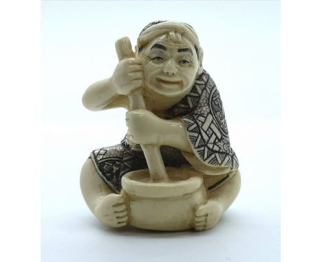A signed carved ivory Japanese netsuke of a man mixing corn flour