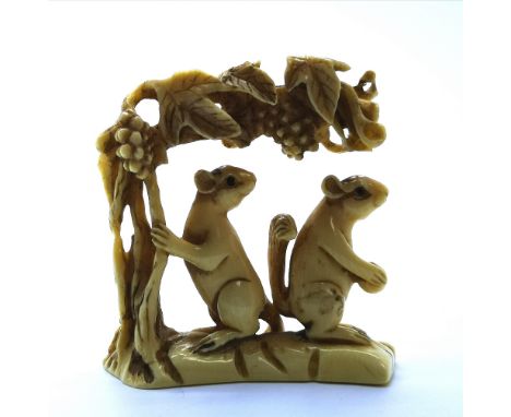 A signed carved ivory Japanese netsuke study of two squirrels feeding from the grape vine