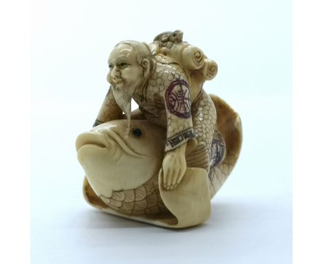 A signed and carved ivory Japanese netsuke of a man with a rat riding on a giant carp