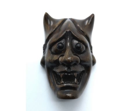 A signed carved fruitwood Japanese netsuke of a demons head