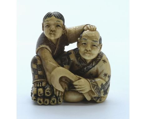 A signed carved ivory Japanese netsuke of a reed cutter sitting with his son