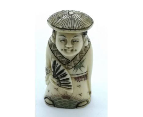 A signed carved ivory Japanese netsuke of a standing man wearing a hat