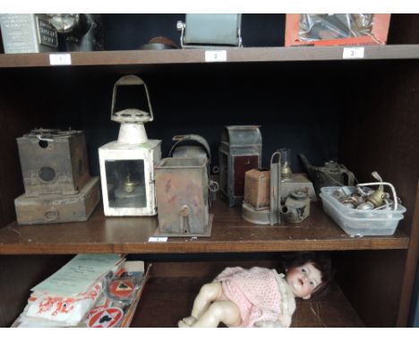 A shelf of various vintage railway and similar oil and parafin lamps with various spares