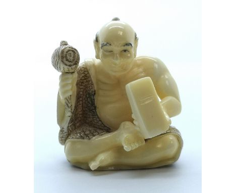 A signed carved ivory Japanese netsuke of a seated carver working