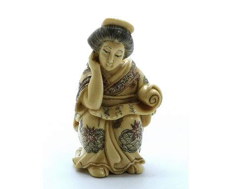 A signed carved ivory Japanese netsuke of a geisha reading a scroll