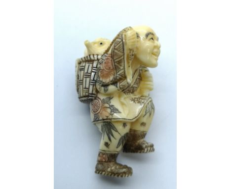 A signed carved ivory Japanese netsuke of a fisherman carrying an octopus in a basket on his back