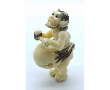 A signed carved ivory Japanese netsuke of a demon beating his drum