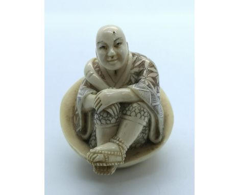 A signed carved ivory Japanese netsuke of a seated wizard