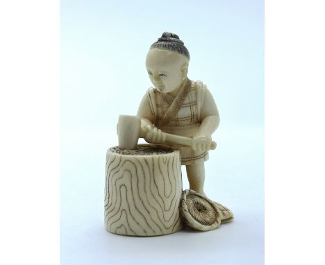 A signed carved ivory Japanese netsuke of a man beating corn