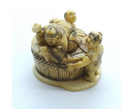 A signed carved ivory Japanese netsuke of three men coopering a barrel
