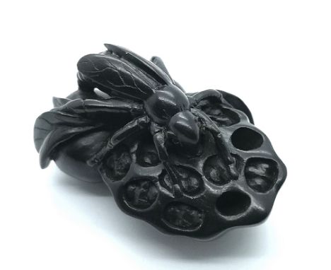 A carved and signed Japanese netsuke of a locust seated on fruit