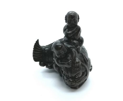 A signed carved wooden Japanese netsuke two boys riding an the back of a fish