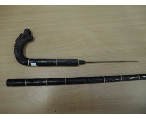 A black wood walking stick with dragon handle, one eye missing, handle converts into a dagger with 7inch blade