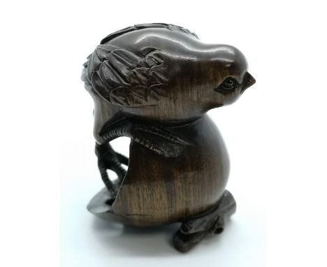 A carved and signed fruitwood Japanese netsuke of a bird hatching from and egg