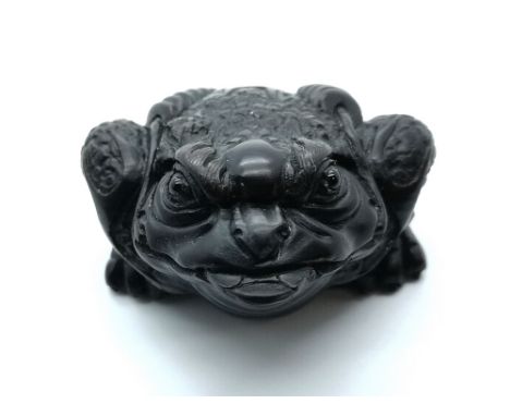 A carved and signed  fruitwood Japanese netsuke of a rich toad with string of coins on his back and coin in his mouth