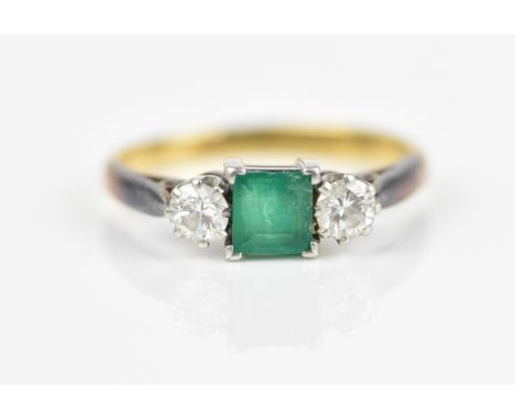 An 18ct yellow gold, platinum, emerald and diamond ring, with central princess cut emerald, flanked with a brilliant cut diam