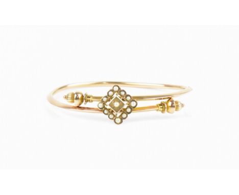 A Victorian rose metal and seed pearl bangle, the front with pierced diamond shape mount inset with seed pearls, each end wit