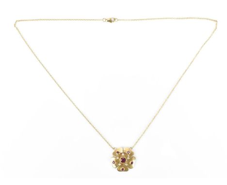 A yellow metal, diamond and ruby necklace, the flower shaped pedant centered with a round cut ruby in rubover setting within 