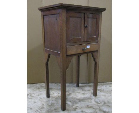 A small oak freestanding side cupboard enclosed by a pair of rectangular panelled doors over a long drawer raised on square t