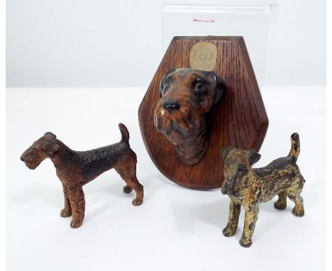 Two cold painted bronze models of fox terriers and a further ceramic fox terrier mask mounted on an oak board 