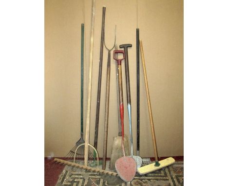 A small collection of long handled tools to include a two pronged pitchfork, a vintage hay rake, two peat shovels, etc 