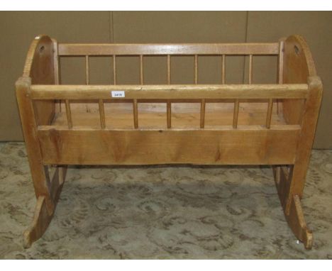 A stripped pine cot of tapered form with open stick rails and shaped rockers 