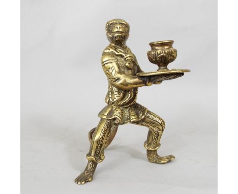 A heavy cast brass candlestick in the form of a monkey in costume supporting a tray and vase, 90cm high 