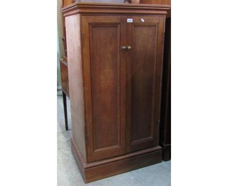 A floorstanding side cupboard enclosed by a pair of slender rectangular panelled doors, the interior plywood shelved, togethe