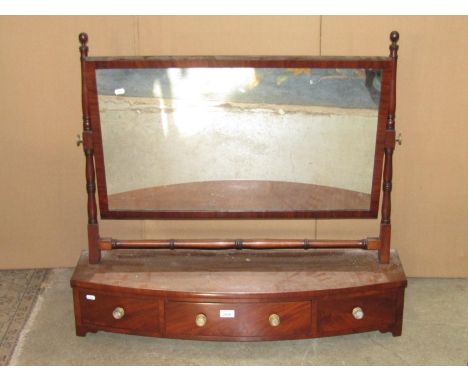 An early 19th century mahogany toilet mirror, the wide rectangular plate raised on ring turned column supports over a bow fro