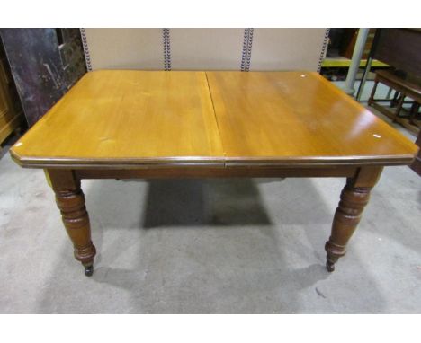 An Edwardian oak and walnut wind-out extending dining table of rectangular form with canted corners, moulded outline and sing