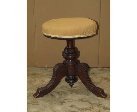 A late Victorian walnut piano stool with circular revolving adjustable upholstered seat raised on a turned pillar and swept t