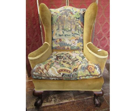 A substantial Georgian style wing chair raised on carved supports with claw and ball feet, tapestry work seat and back panels